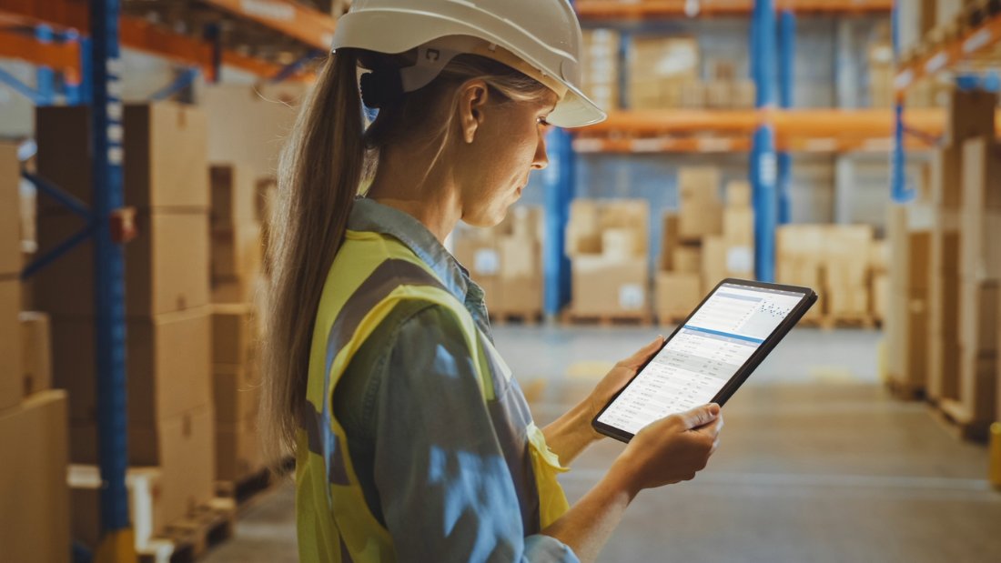 The Role of Product Information Management in B2B Ecommerce Success Warehouse worker using a tablet to manage inventory, highlighting successful product information management in B2B ecommerce